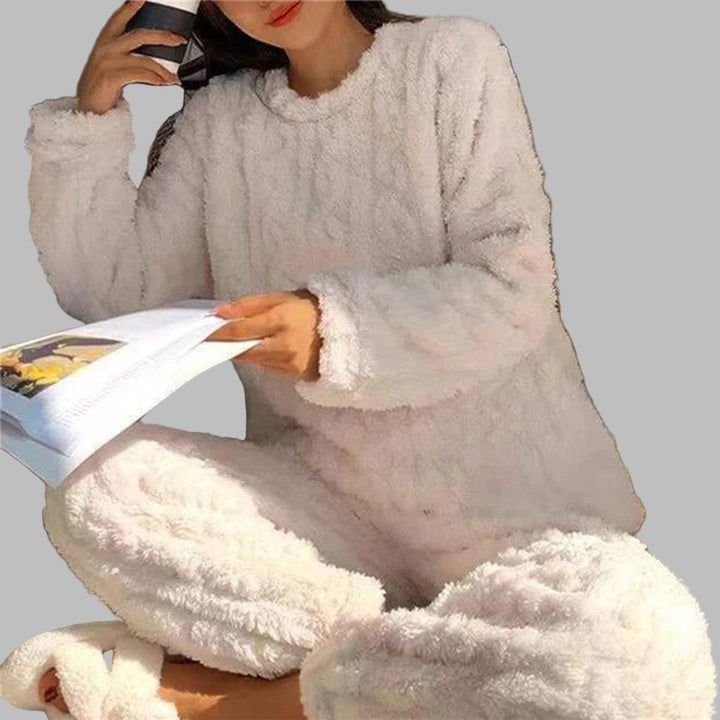 Vrouw in witte, zachte en knusse pyjamaset met mok en tijdschrift. Comfortabele loungewear, perfect voor thuis ontspannen.