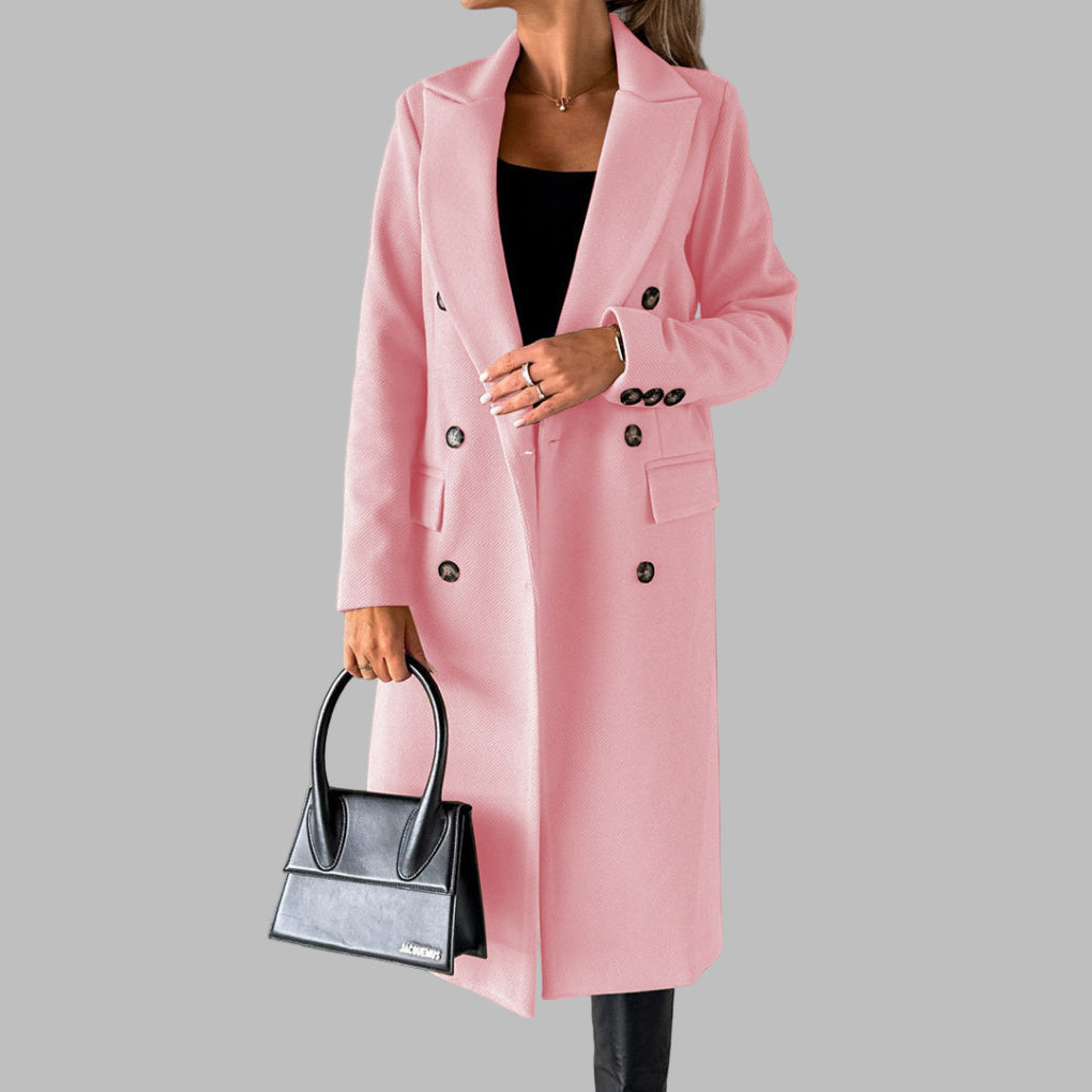 Vrouw in roze winterjas met dubbele rij knopen, zwarte top en broek, houdt een zwarte handtas vast. Stijlvolle damesmode, herfst-winter outfit.